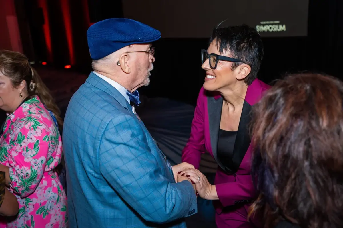 Keynote speaker greeting an attendee with a warm handshake