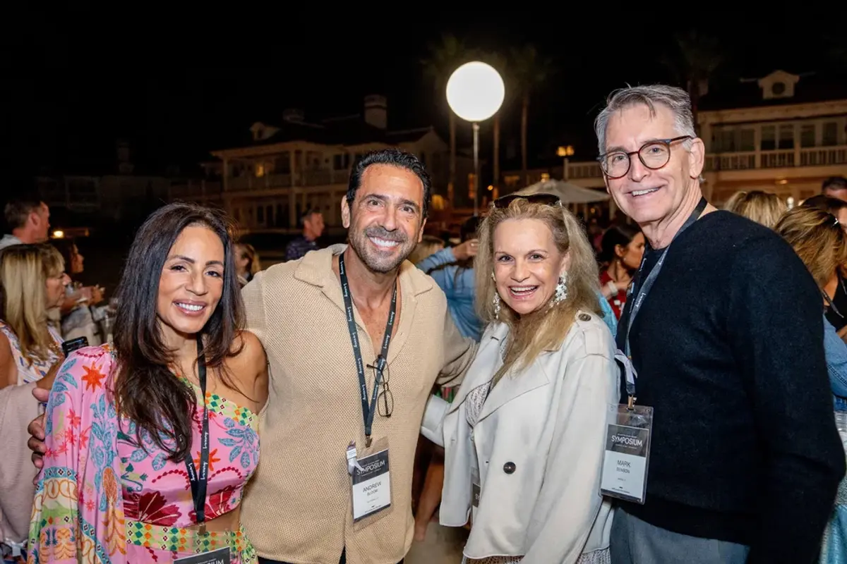 Four attendees smiling together at the KW Luxury beach reception after dark.