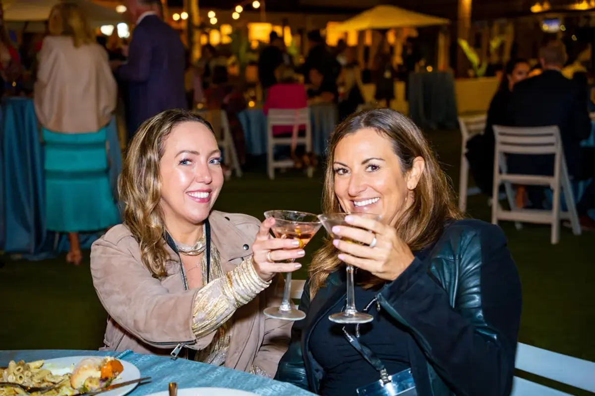 Two attendees smile and toast their glasses