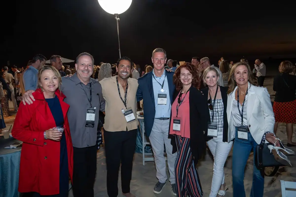 Guests gathered for a KW Luxury evening beach reception, smiling for a group photo.
