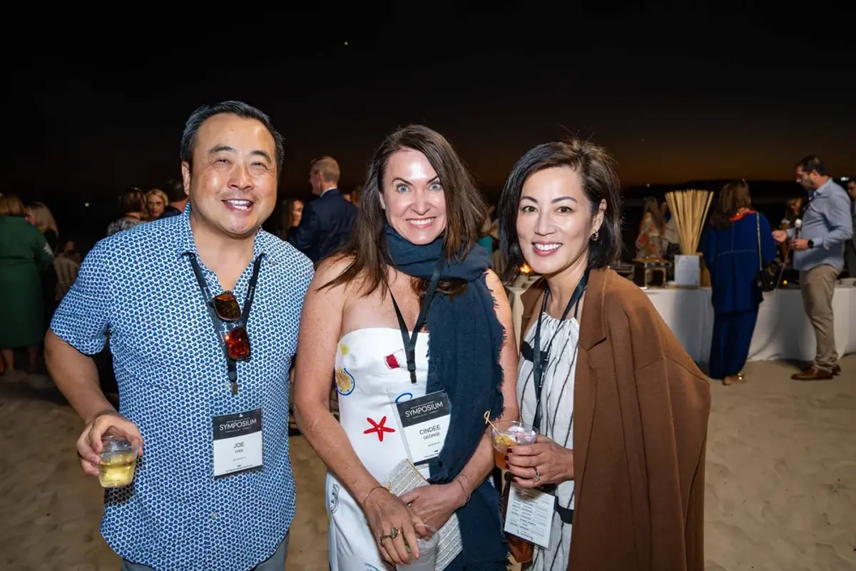 KW Luxury Director Caroline smiling with two attendees during nighttime beach reception.