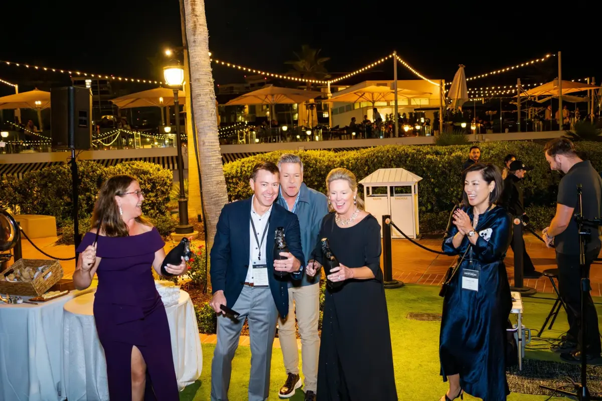 Guests enjoying cocktails at an evening outdoor KW Luxury reception with string lights