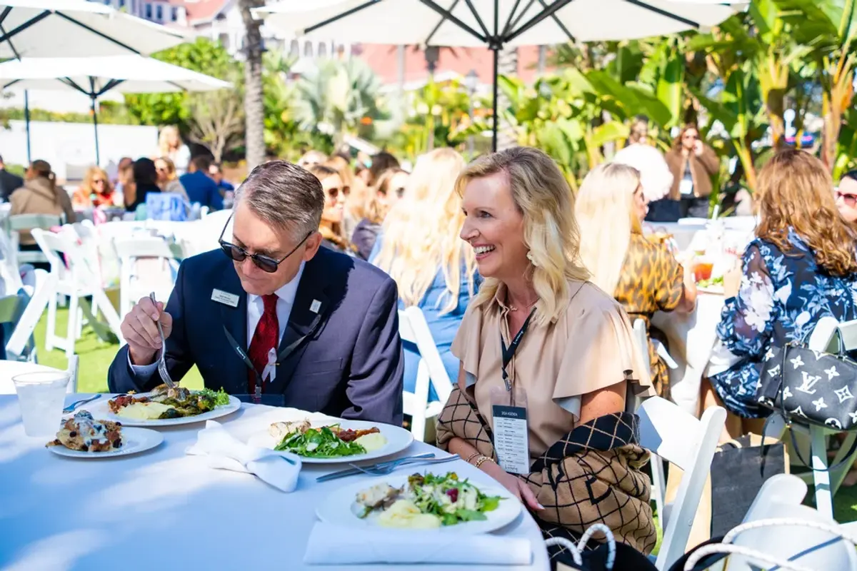 Two attendees smile enjoying lunch outside