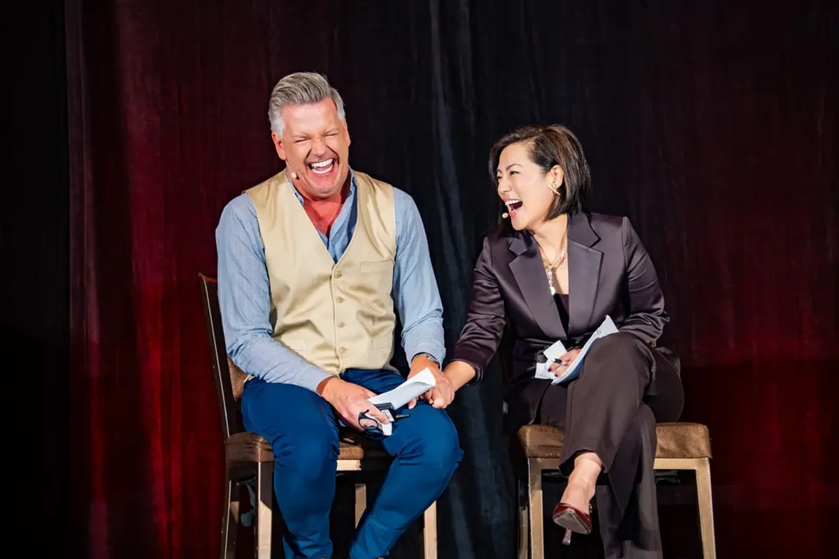 KW Luxury Directors Brady and Caroline laughing while presenting from stage.