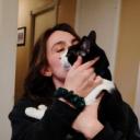 A woman holding a black and white cat.