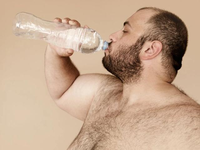Man drinks water from a clear plastic bottle