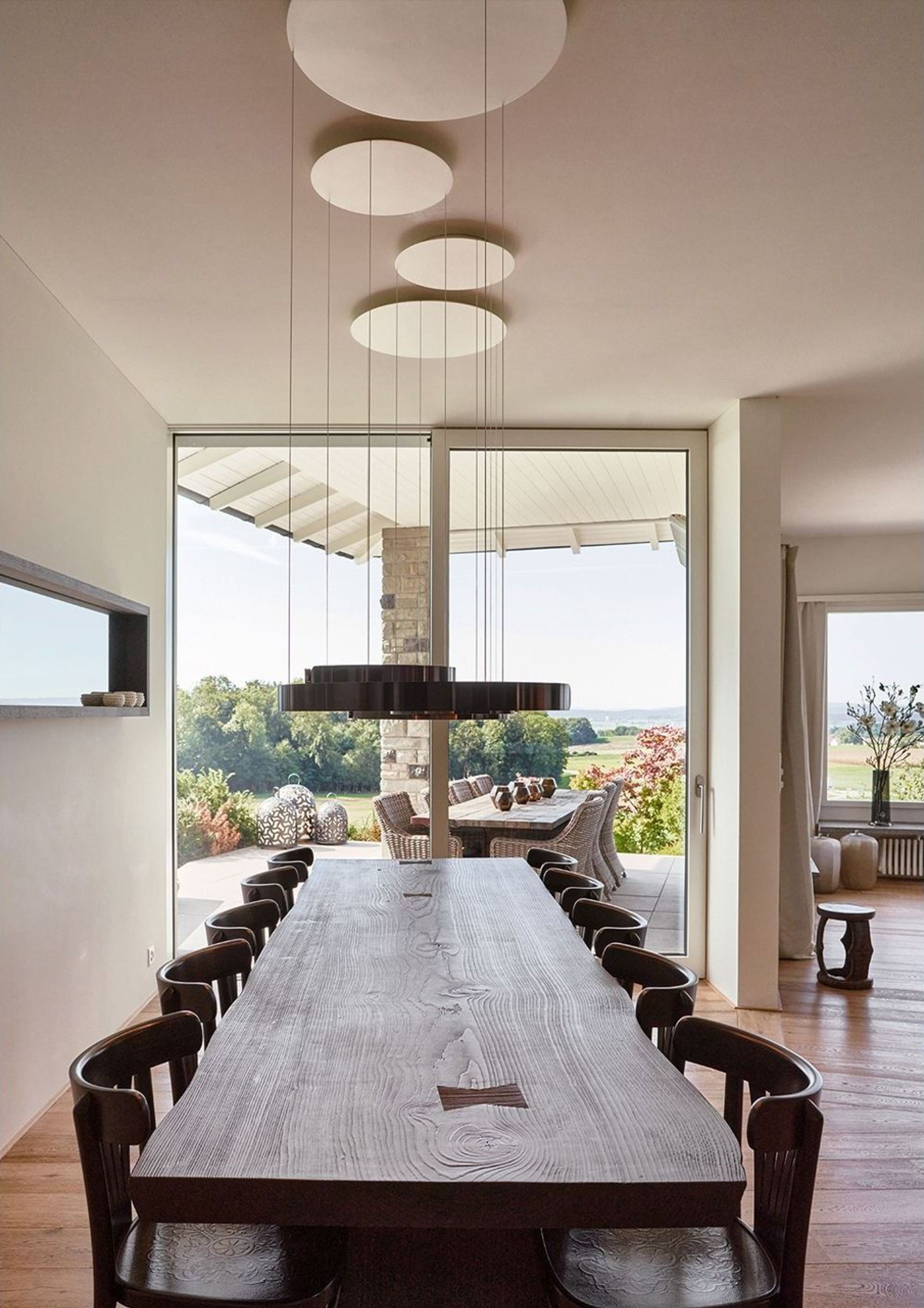 Long dining table with pendant lights and window front – Interiors and landscape, Lufingen
