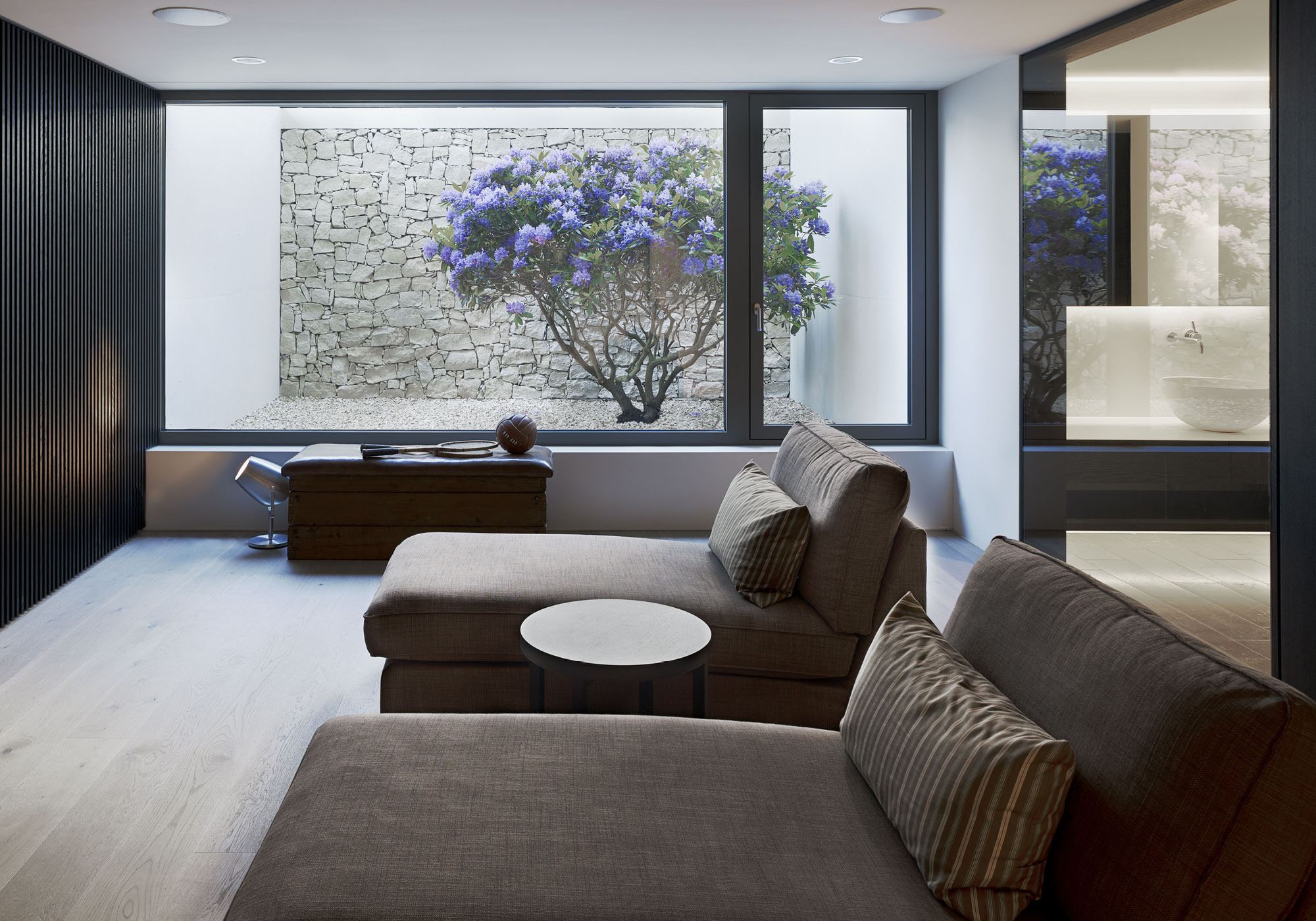 Lounge with light well, flowering tree and natural stone wall – Single-family house in Uitikon