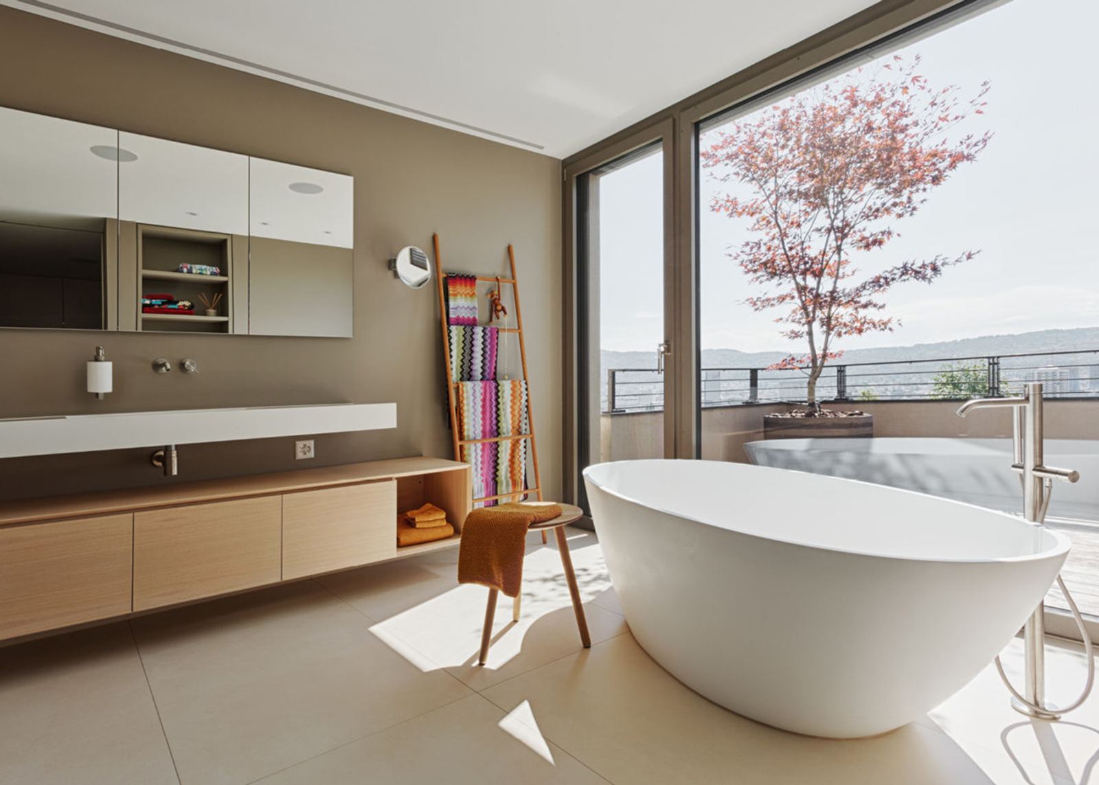 Freestanding bath by the glass front to the terrace