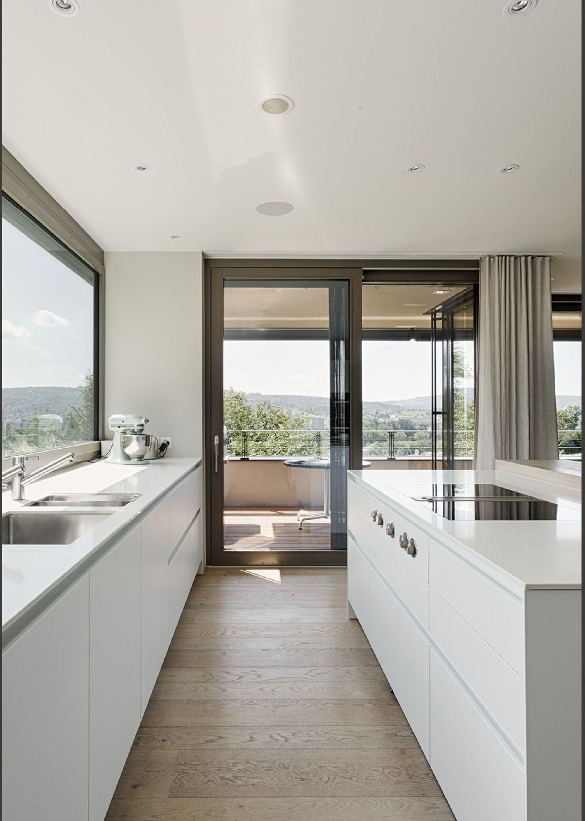 Narrow kitchen with white fronts and balcony door – Single-family house in Zürich