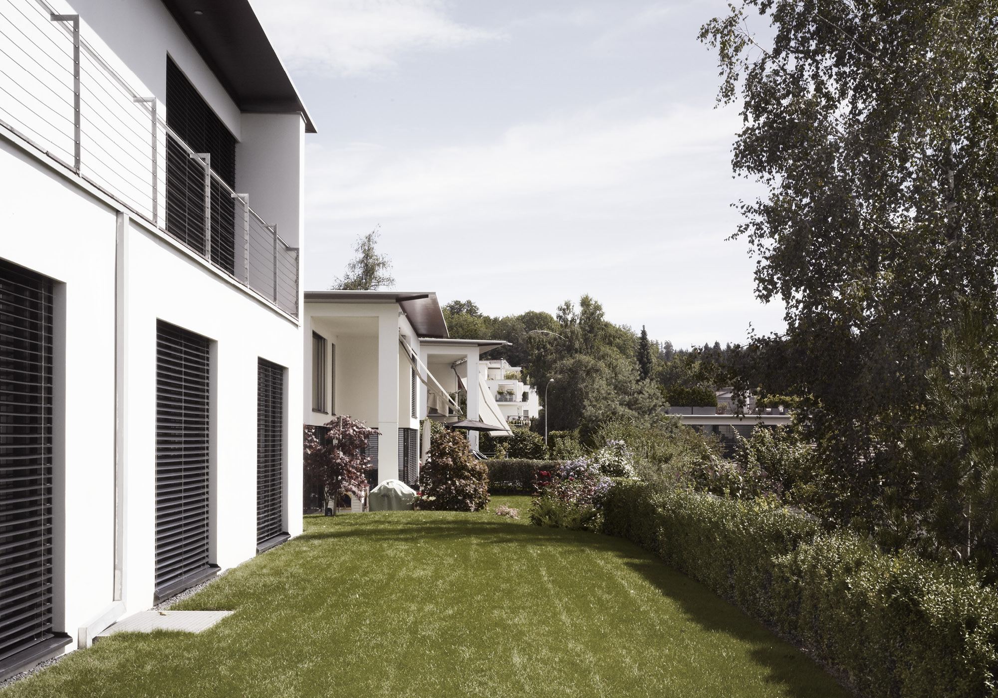 Strip of lawn along the white facade – Interiors and landscape, Uitikon