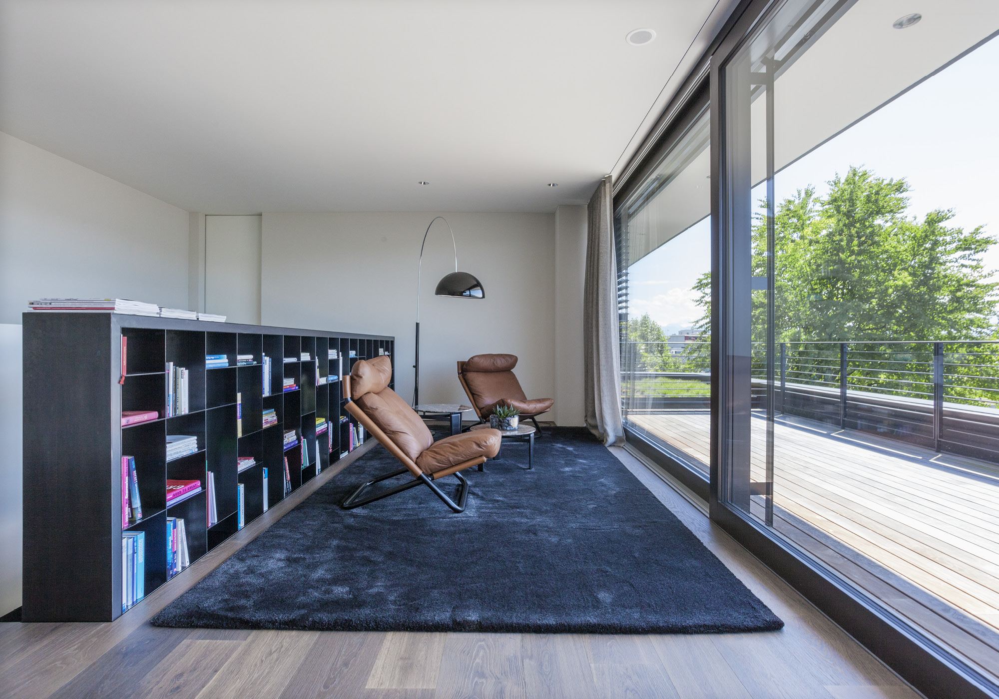 Reading area with lounge chair and shelving wall – Single-family house in Meilen