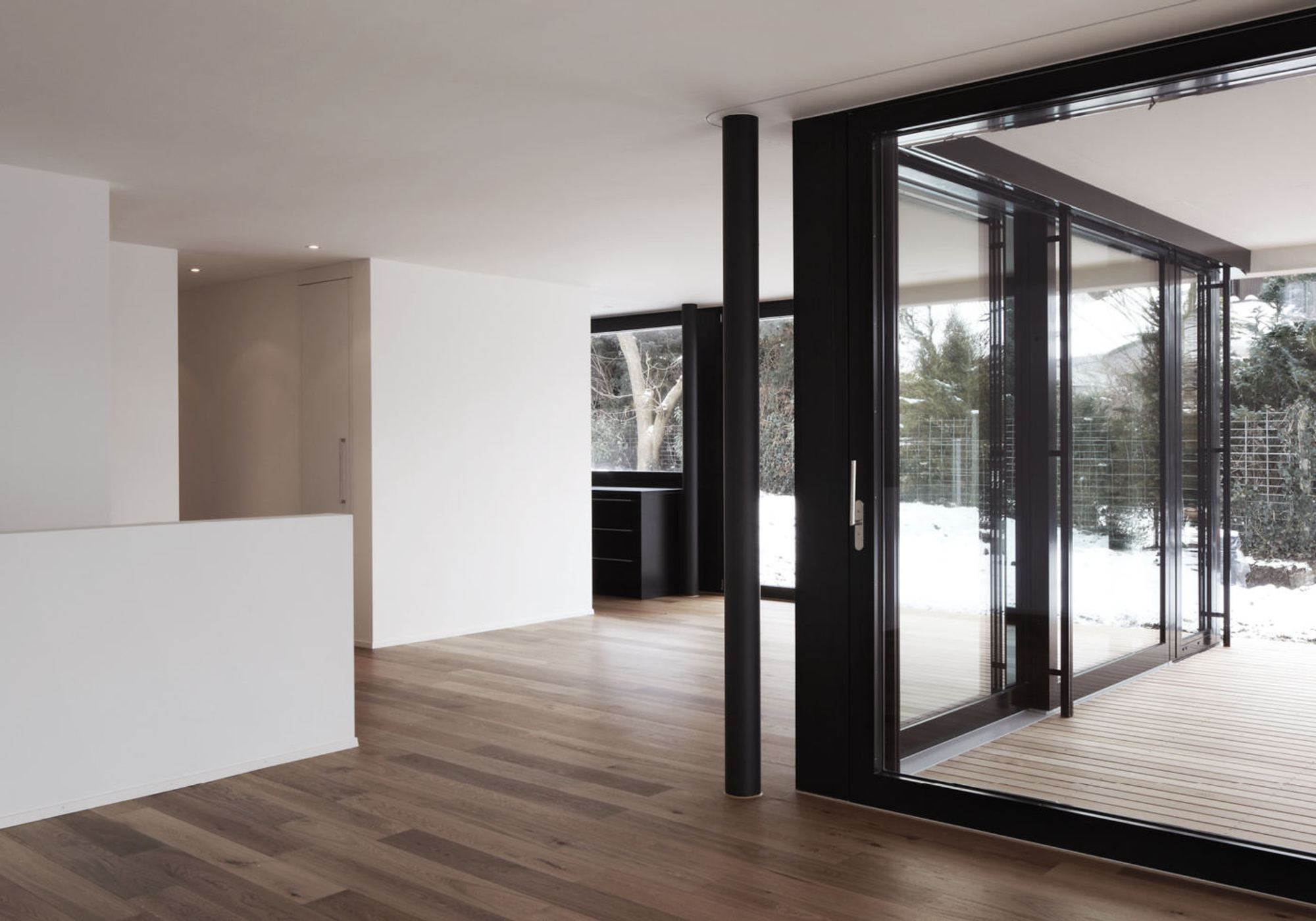 Empty living room with timber floor and sliding window – Apartment building in Uitikon