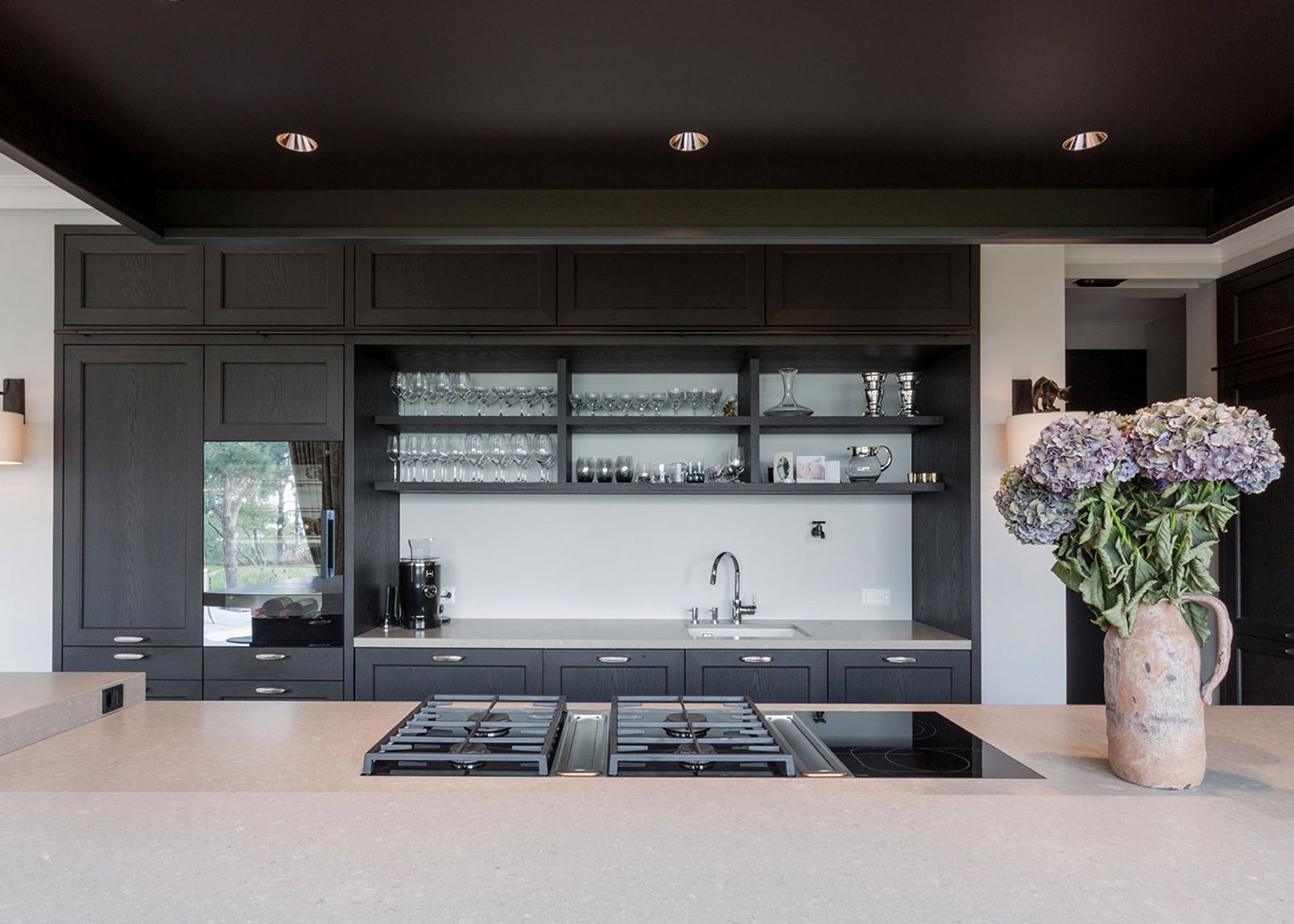 Dark kitchen with open shelves and hydrangeas