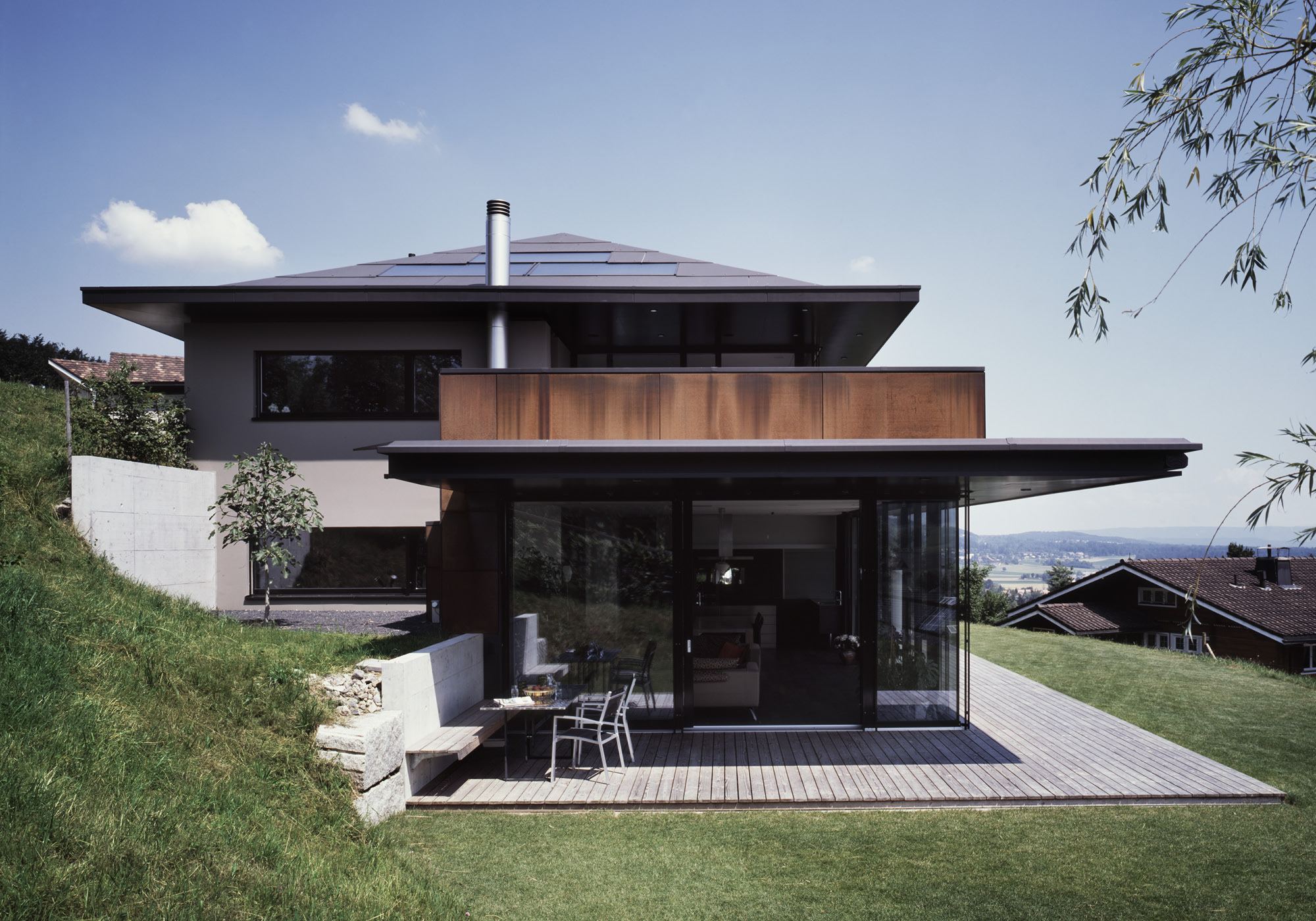 Garden side with hipped roof and timber deck – Single-family house in Bonstetten