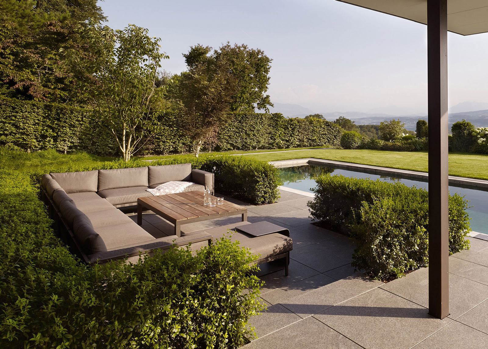 Lounge furniture by the pool between hedges