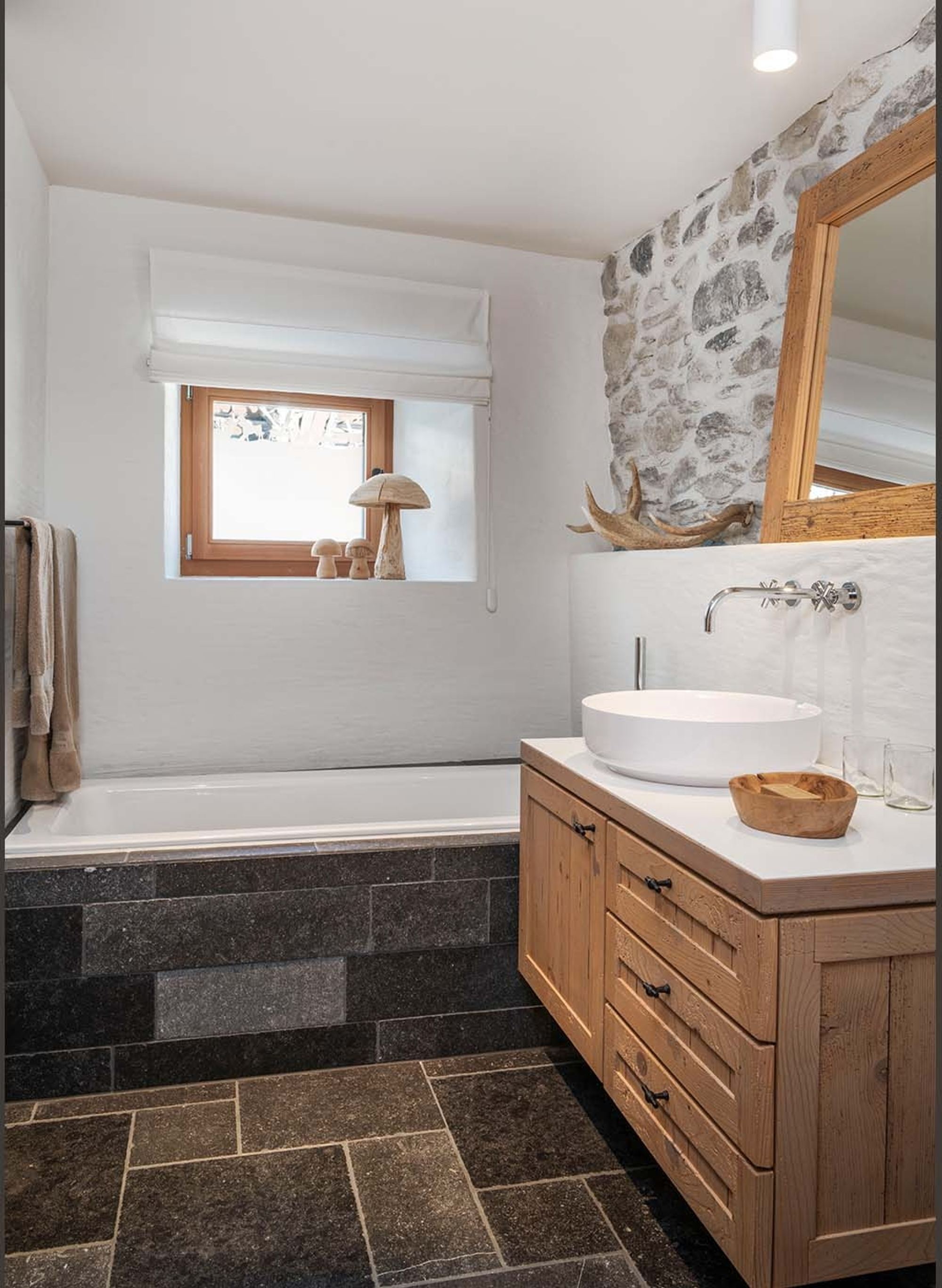 Bathroom with bathtub, timber vanity and stone wall – Historic conversion in Fidaz