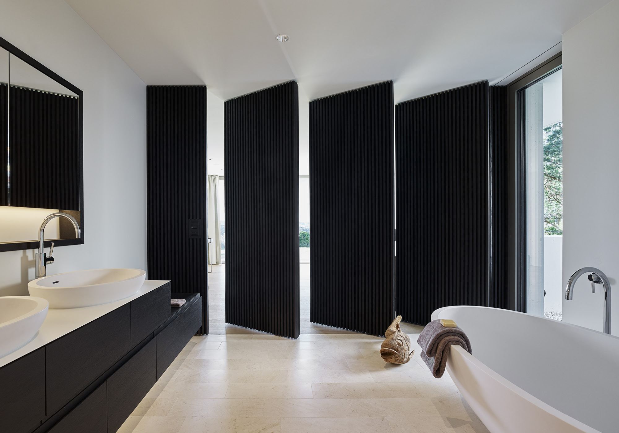 Bathroom with freestanding bath and slatted doors – Single-family house in Uitikon