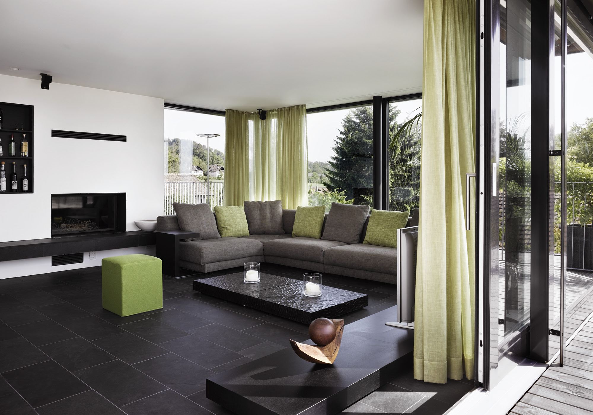 Living room with corner sofa and green curtains – Apartment building in Uitikon