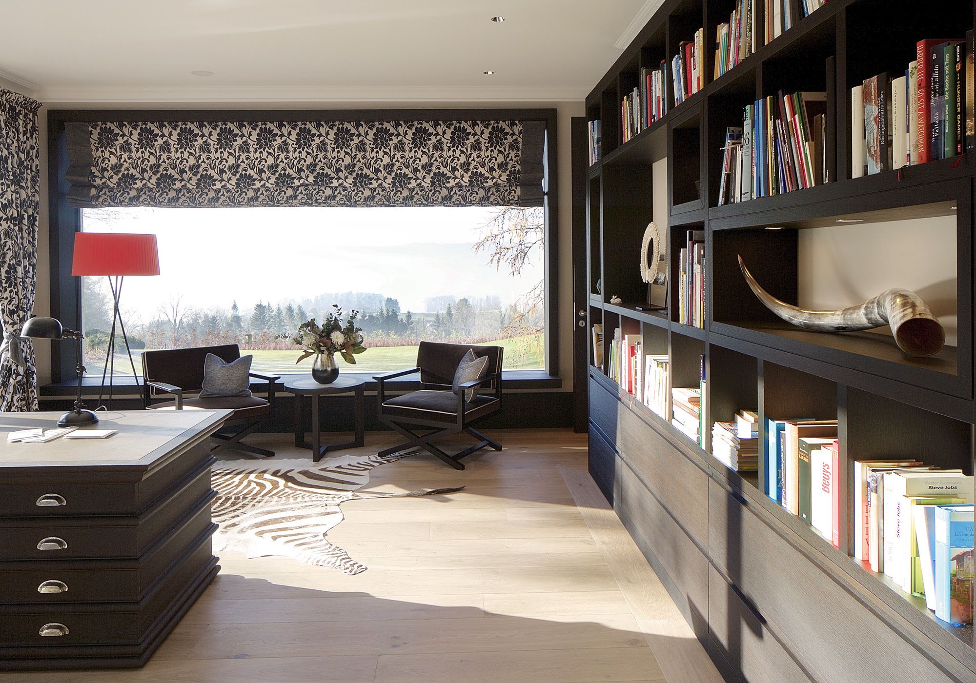 Library with book wall and green view – Single-family house in Herrliberg