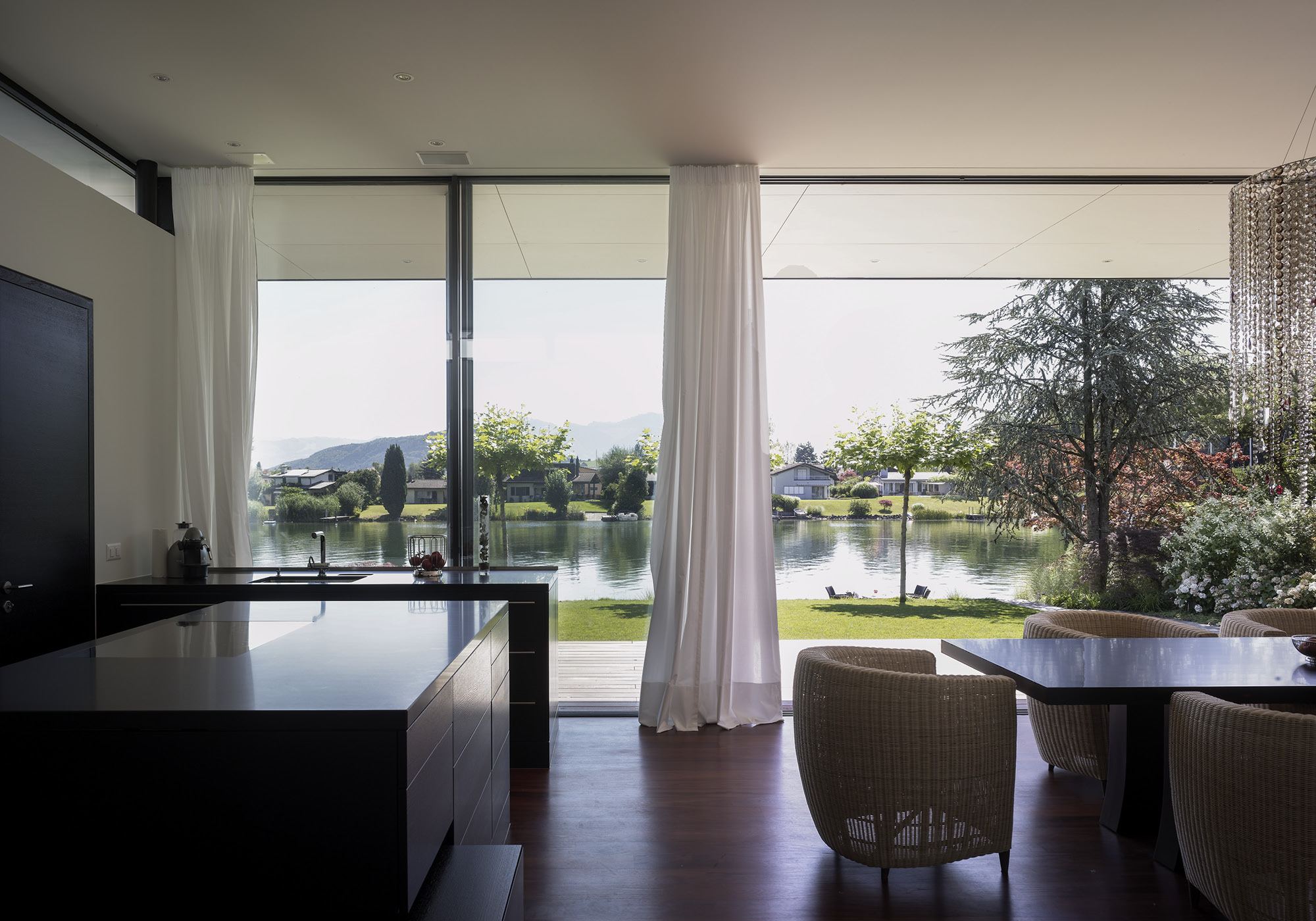 Dining area with armchairs by the glass front facing the water – Single-family house in Lachen