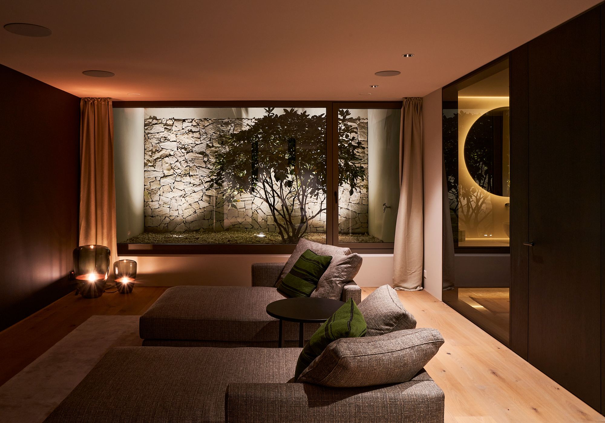 Lounge with light well, trees and natural stone wall – Single-family house in Uitikon