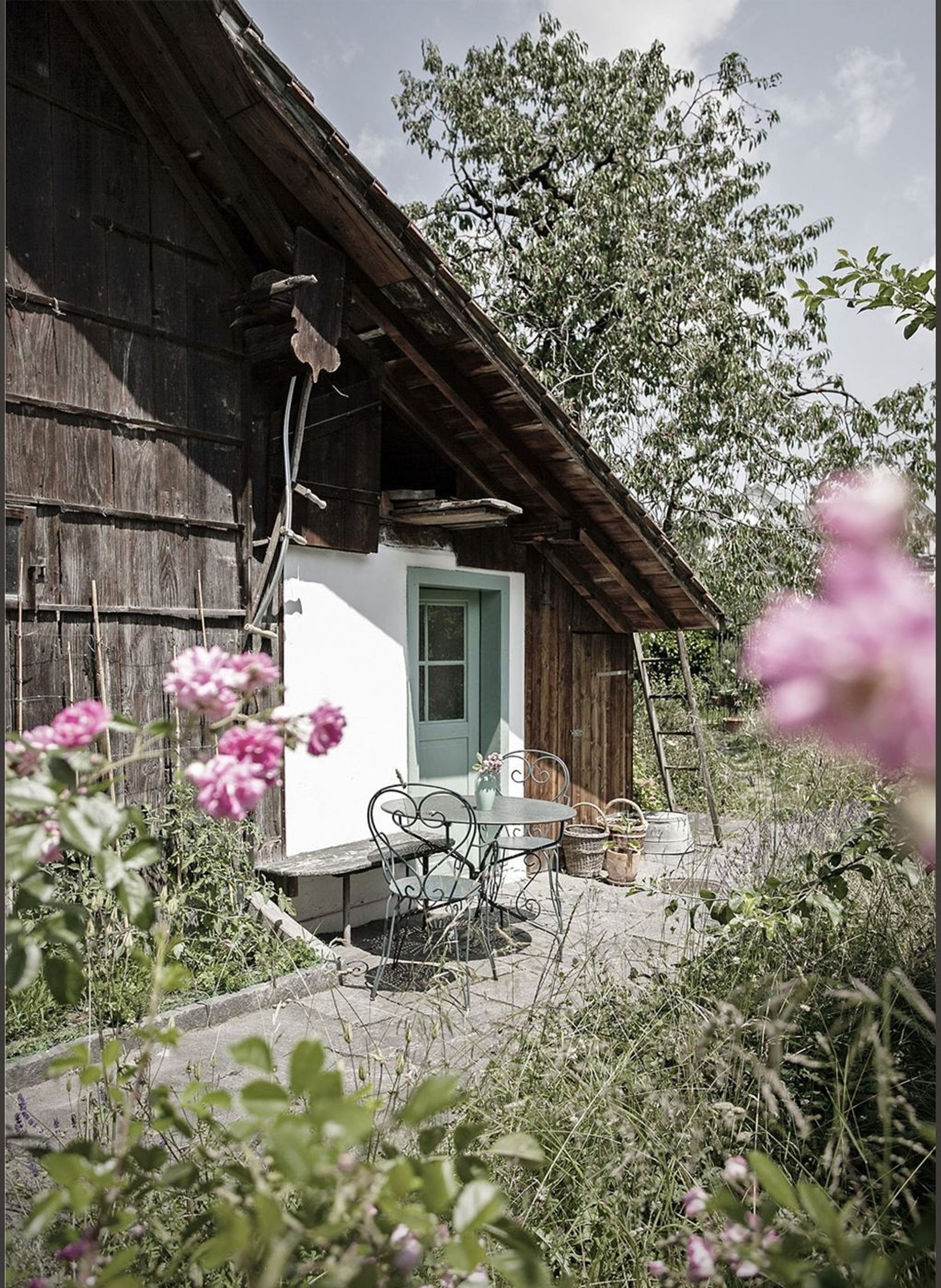 Timber facade with peonies and seating area – Historic conversion in Uerikon