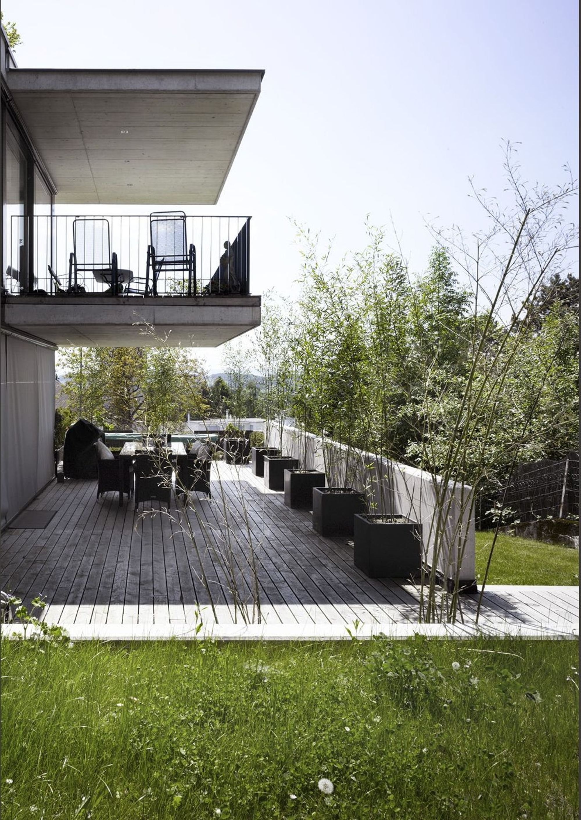 Timber terrace with table below the balcony – Apartment building in Uitikon