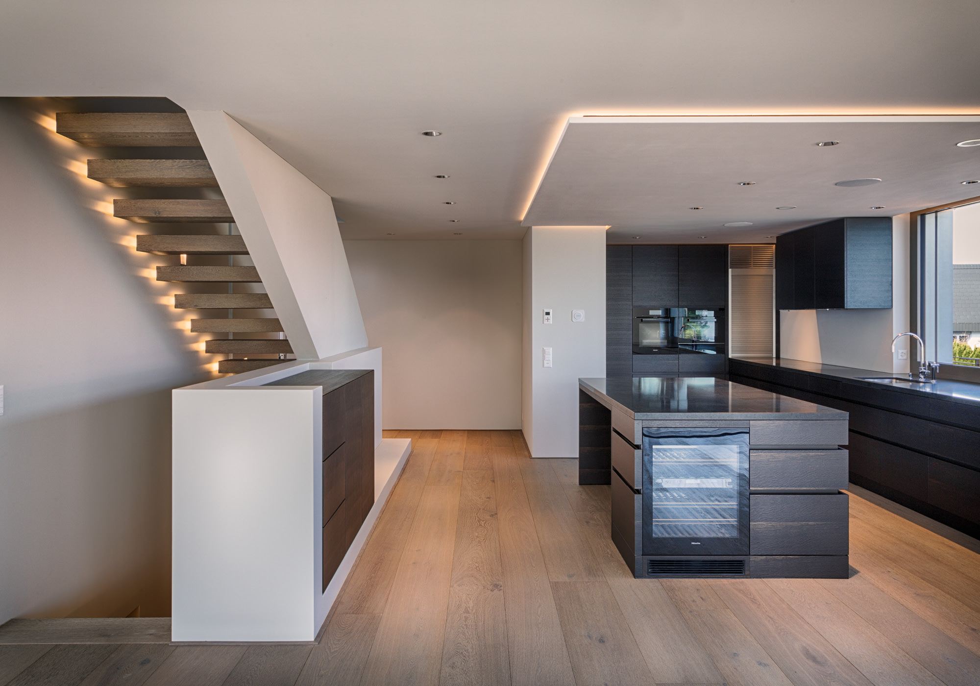 Cantilevered timber staircase with light strip next to the kitchen – Single-family house in Wollerau