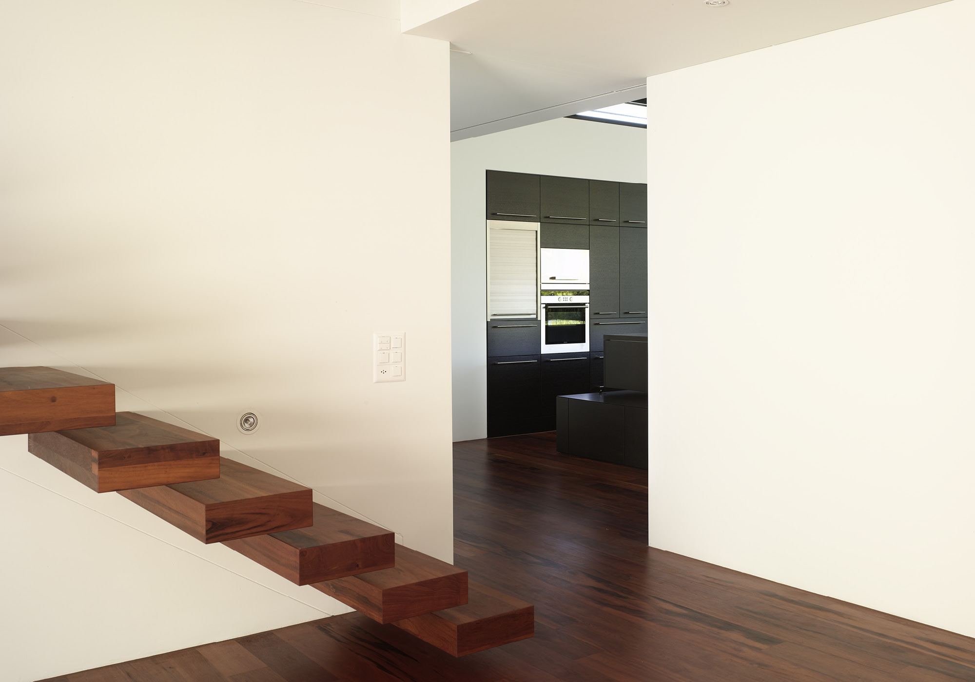 Floating timber staircase against a white wall – Single-family house in Lachen