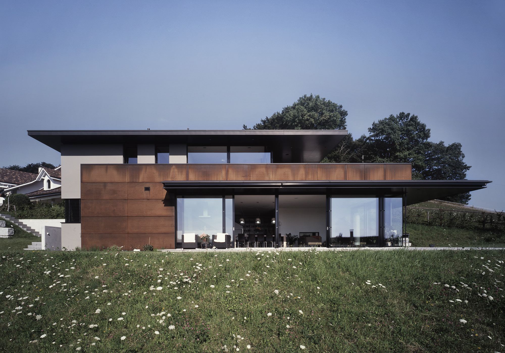Low house with Corten steel facade on the slope – Single-family house in Bonstetten