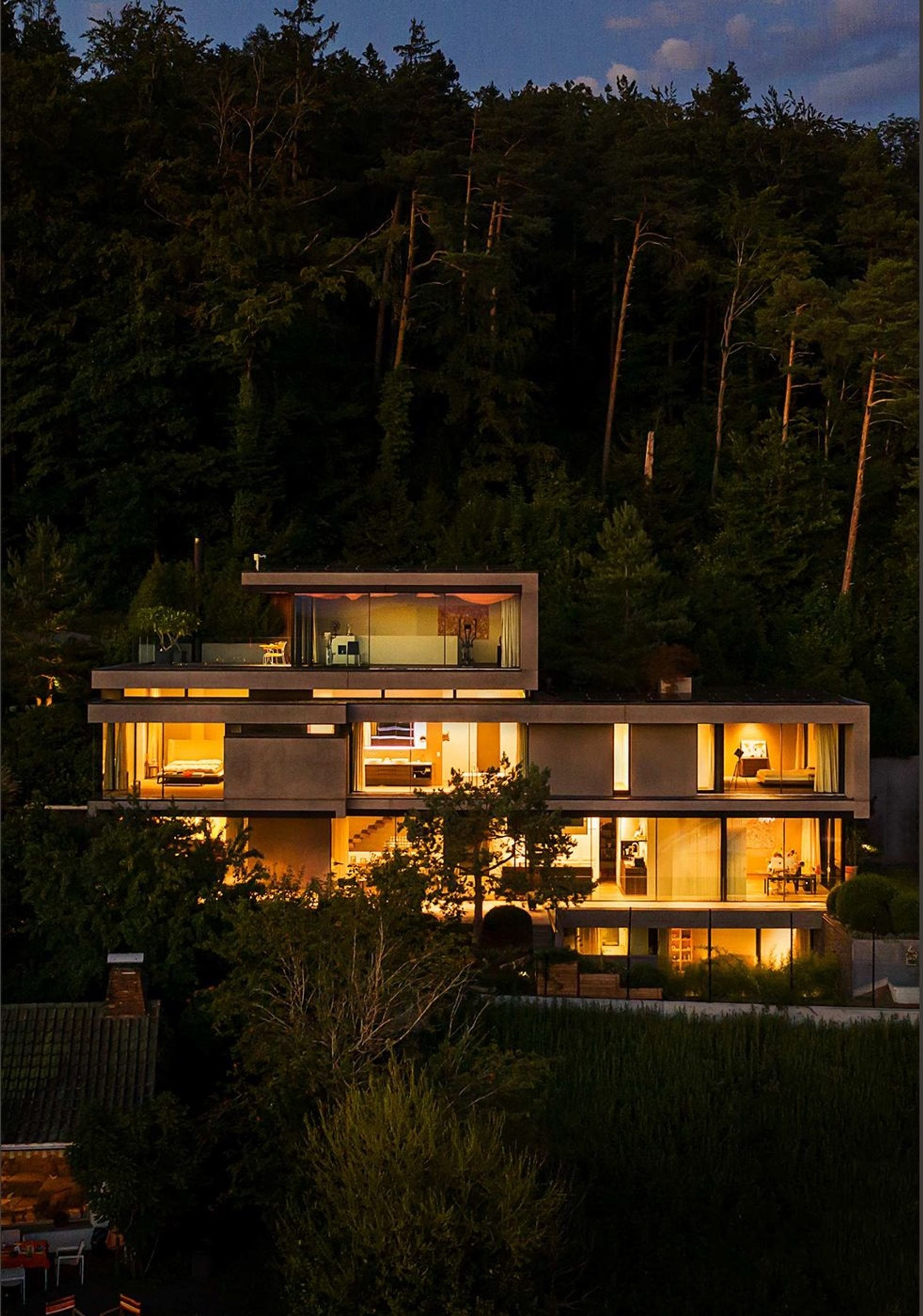 Illuminated house in the woods at night – Single-family house in Uitikon