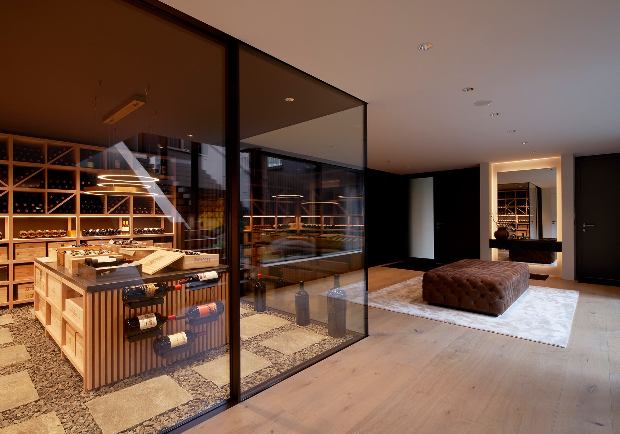 Wine cellar behind a glass wall with timber shelving – Single-family house in Schindellegi
