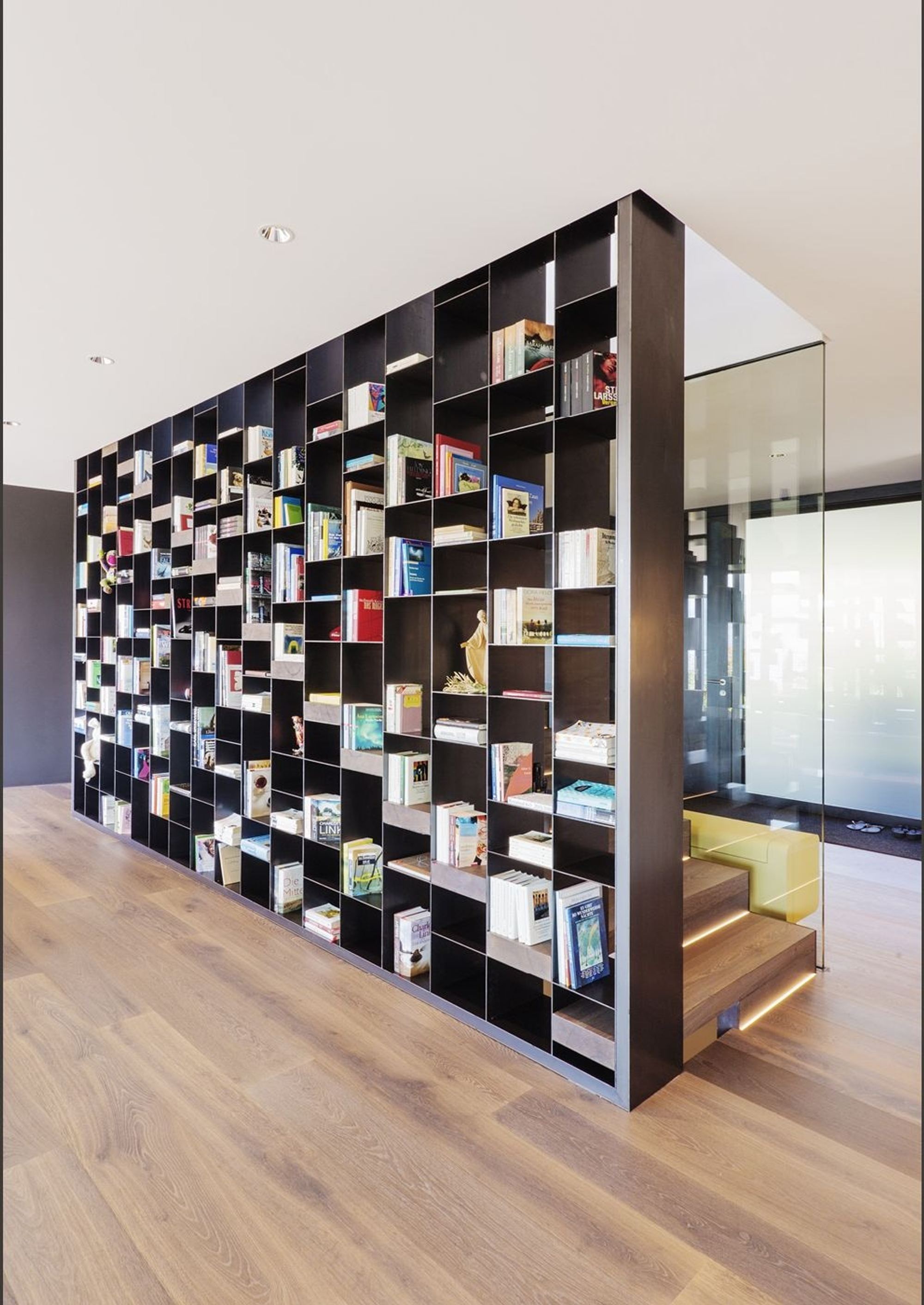 Floor-to-ceiling bookshelf as room divider – Single-family house in Meilen