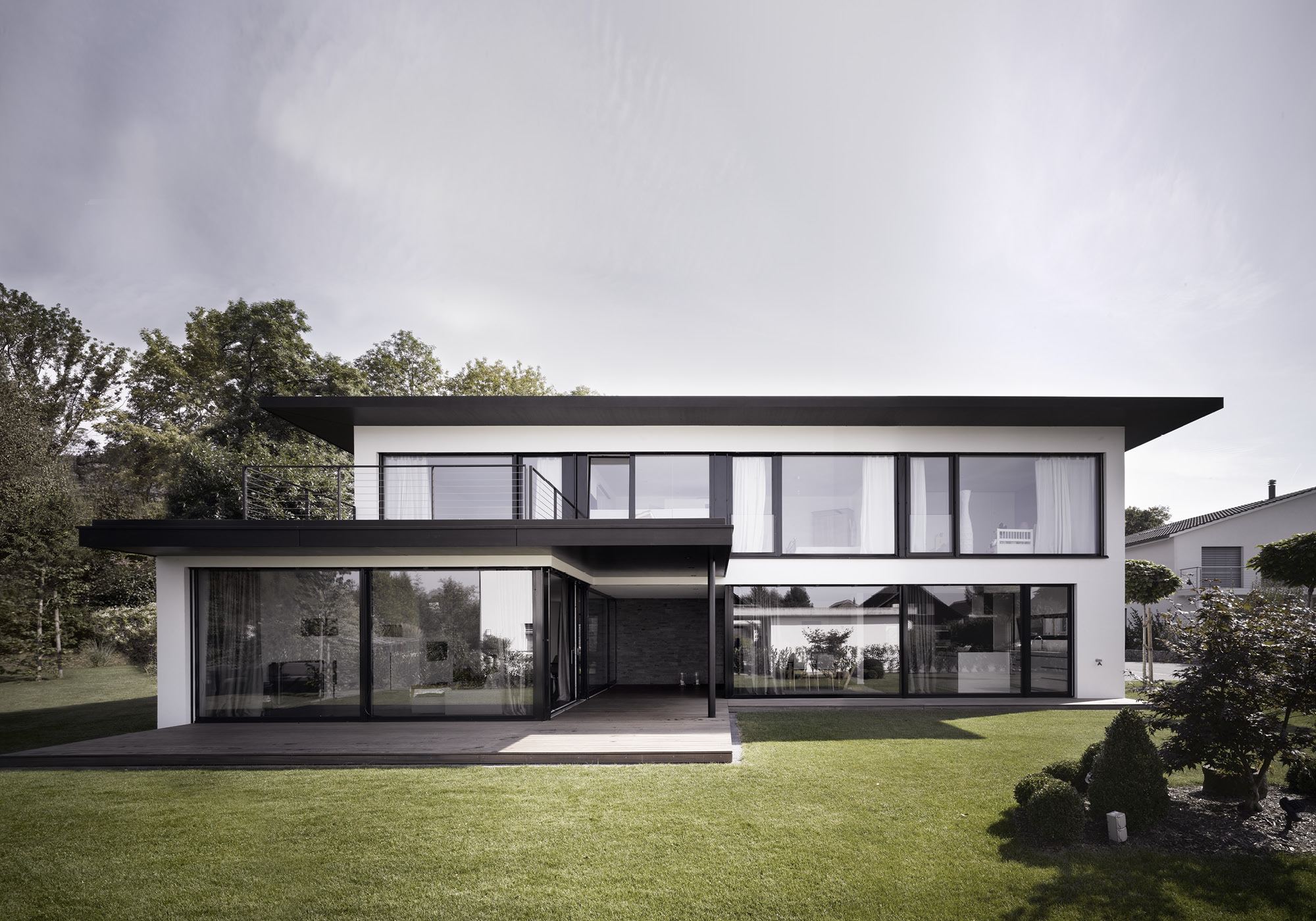White house with low hipped roof and glass front – Single-family house in Möriken