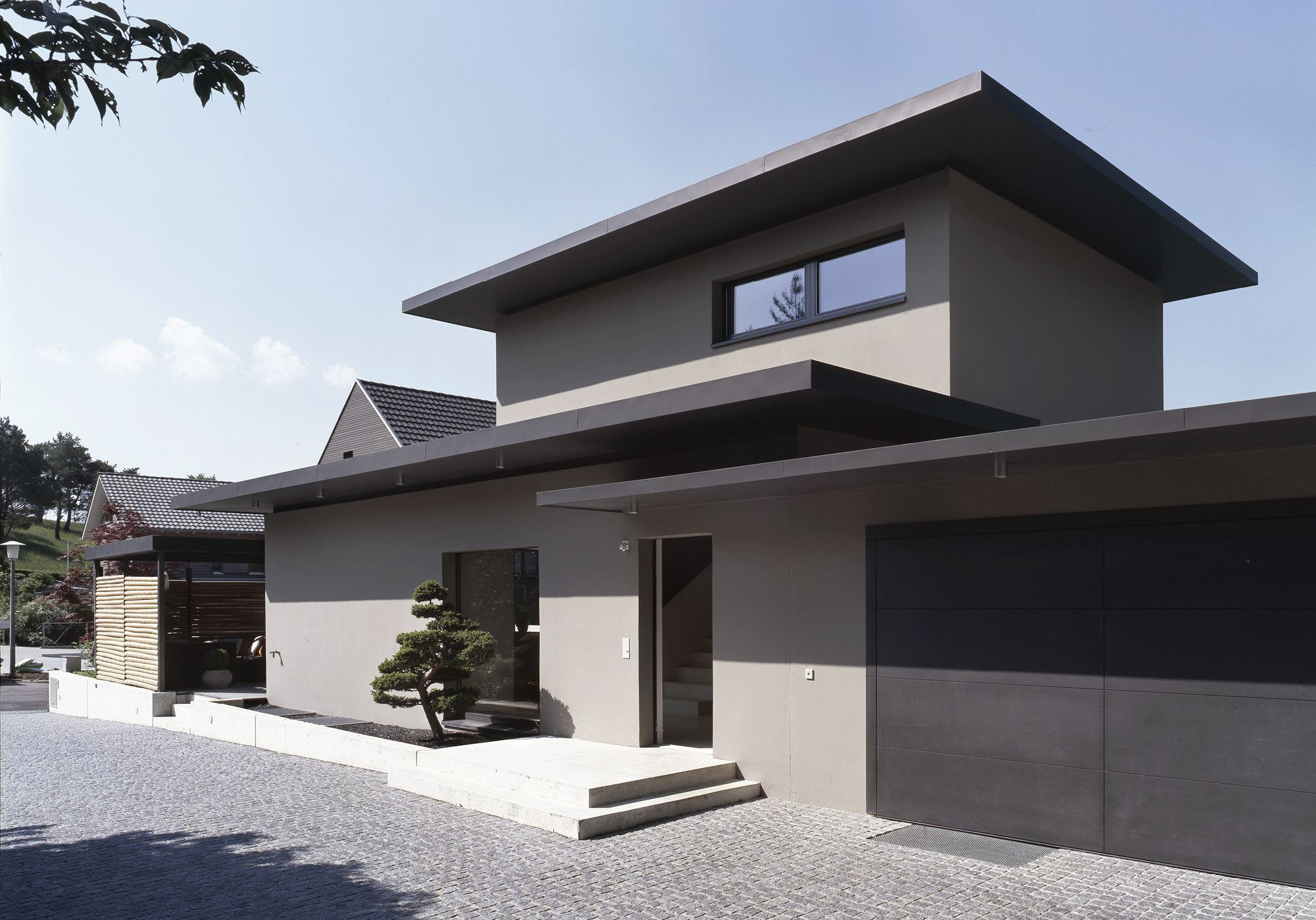 Entrance facade with garage and topiary – Single-family house in Uitikon