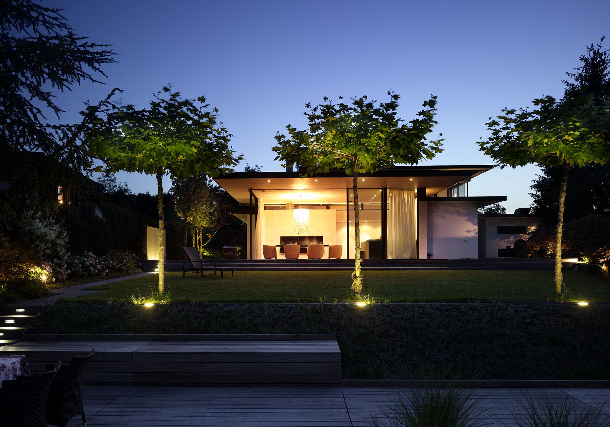 Illuminated garden with trees in the evening – Single-family house in Lachen