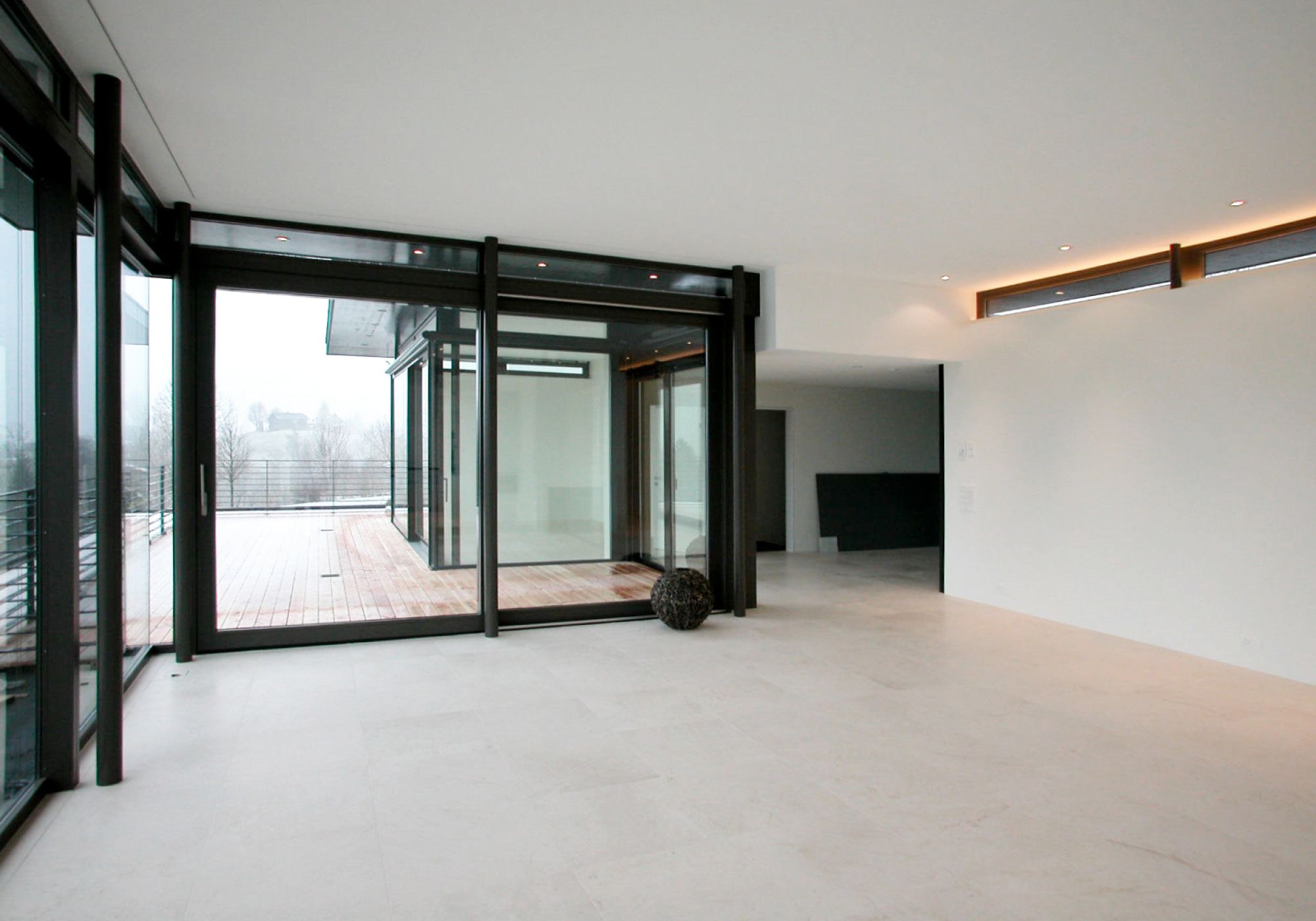 Empty room with glass front and stone floor – Single-family house in Teufen