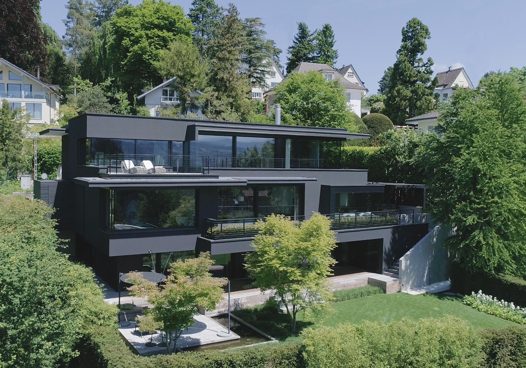 Terraced hillside house with dark facade and garden – Single-family house in Meilen