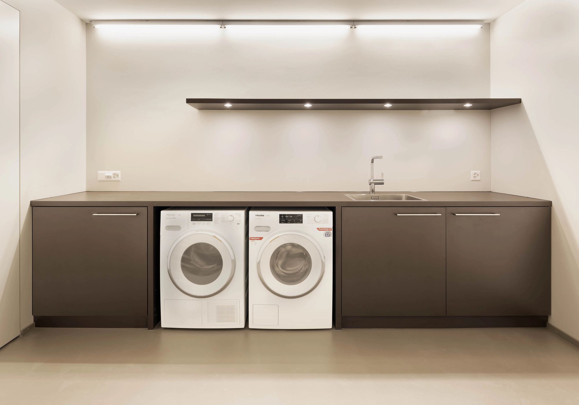 Laundry room with dark cabinets and two machines – Single-family house in Uitikon