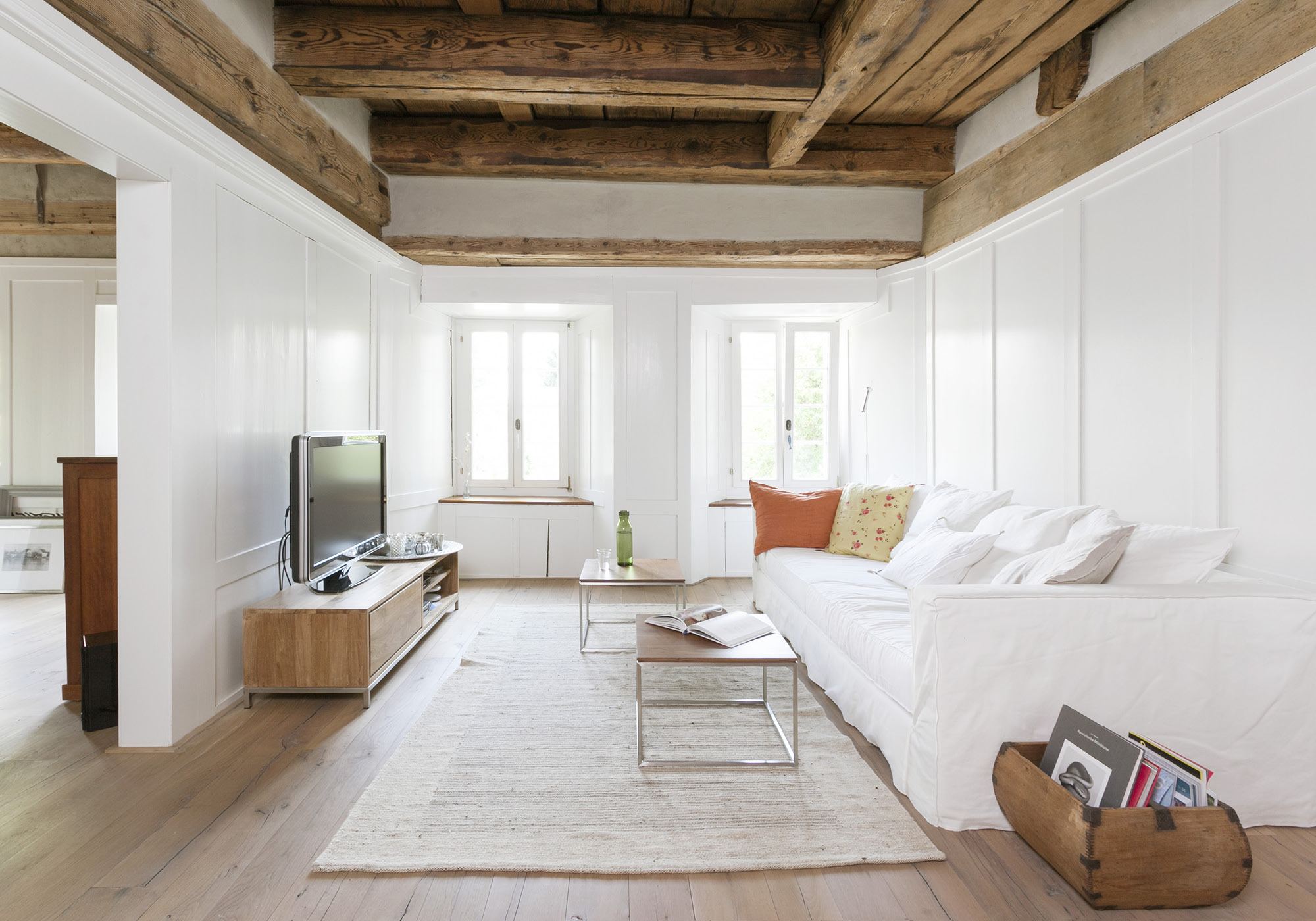 Parlour with timber beam ceiling and white sofa – Historic conversion in Uerikon