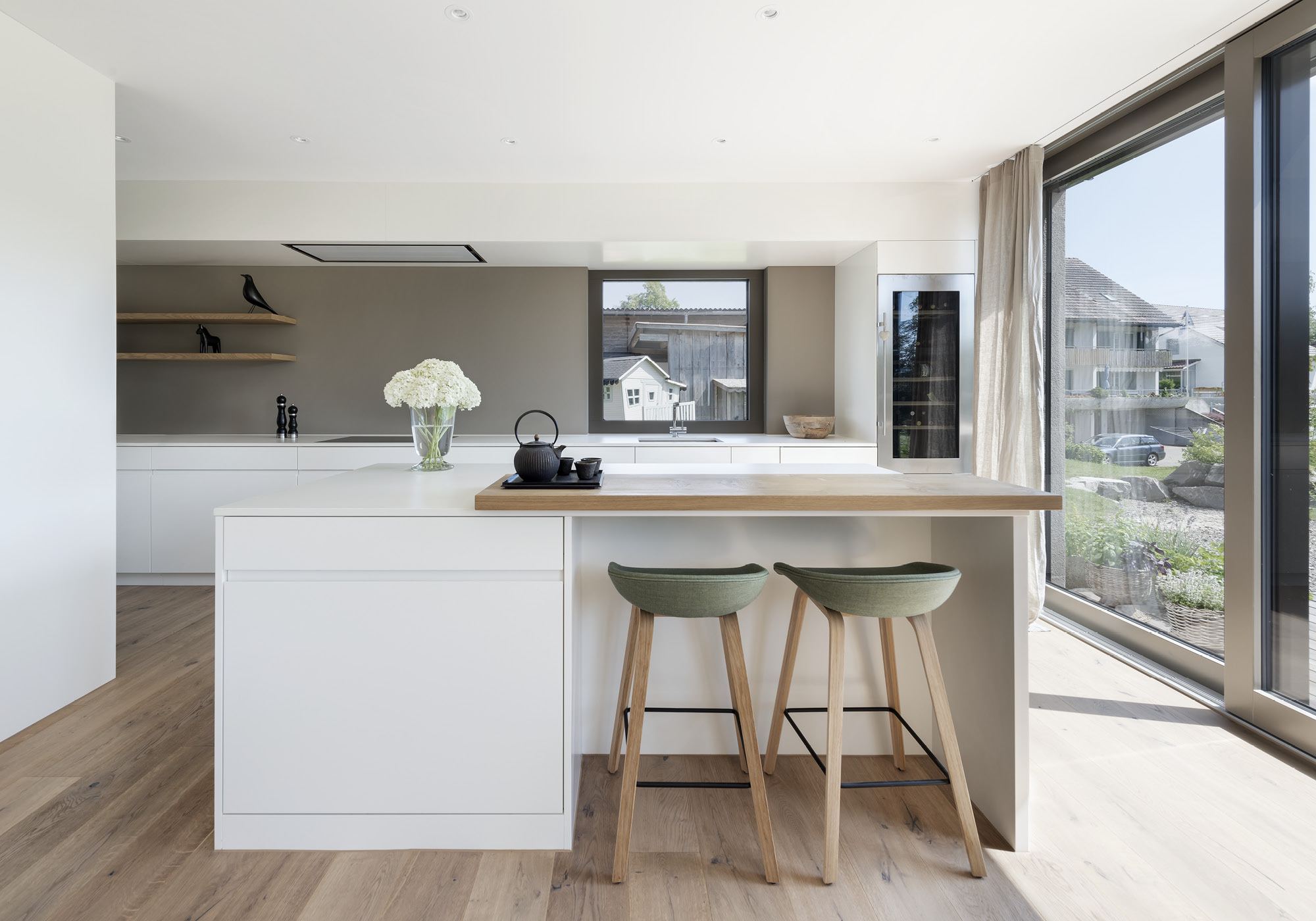 Kitchen with white island and bar stools – Single-family house in Grüningen