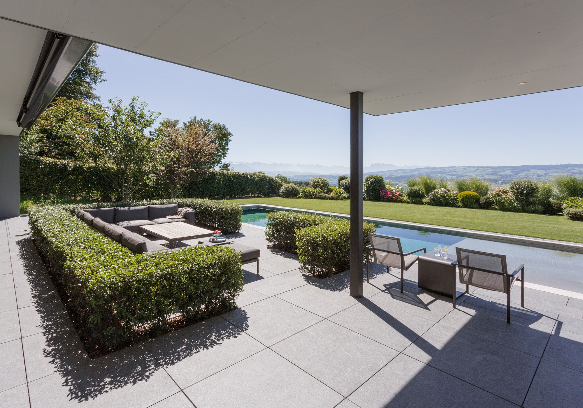 Covered seating area overlooking pool and landscape – Single-family house in Oberwil-Lieli