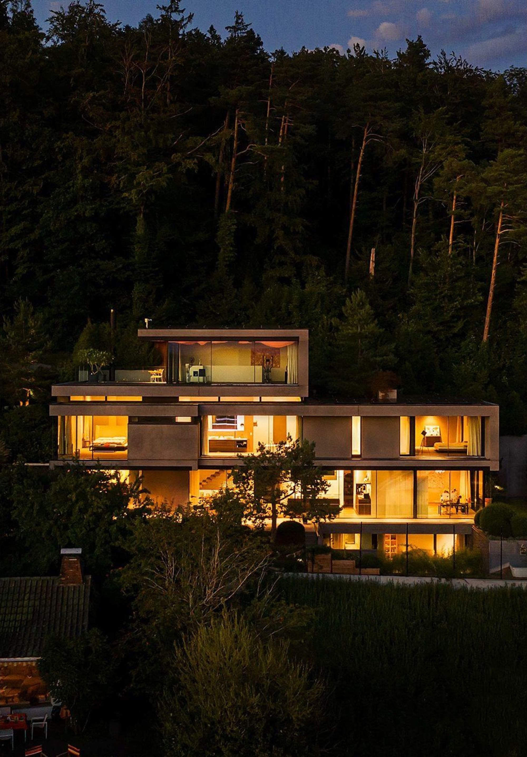 Illuminated house in the woods at night – Single-family house in Uitikon