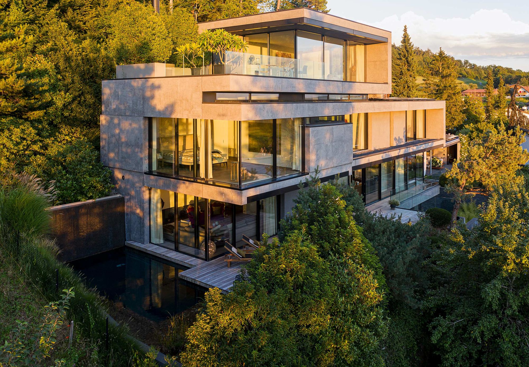 Concrete volumes with glass fronts above a water basin – Single-family house in Uitikon