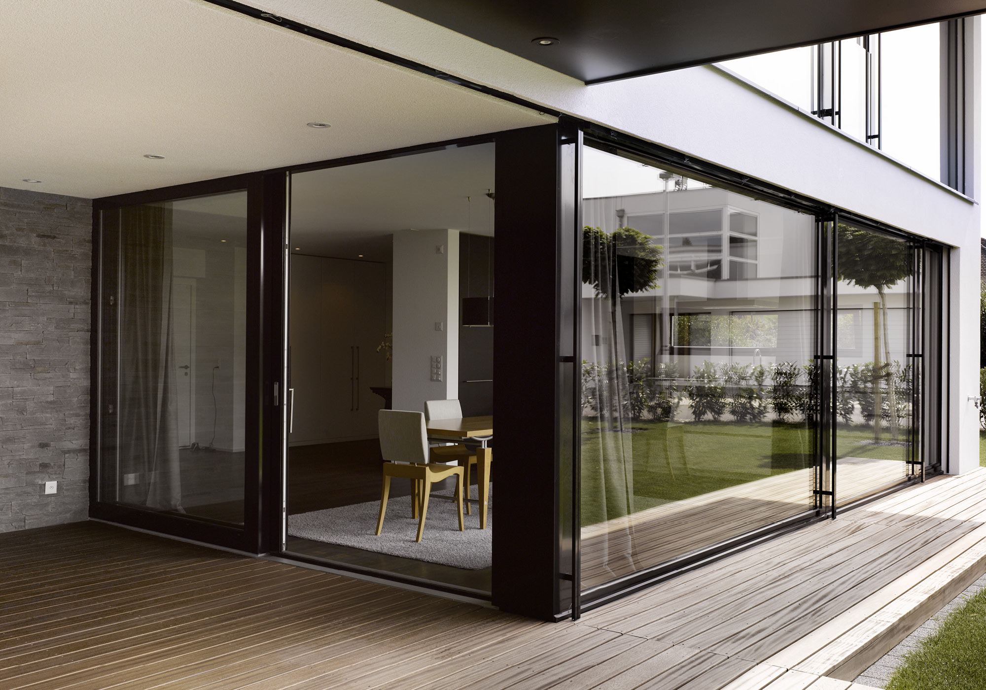 Glass front with timber terrace and stone wall – Single-family house in Möriken