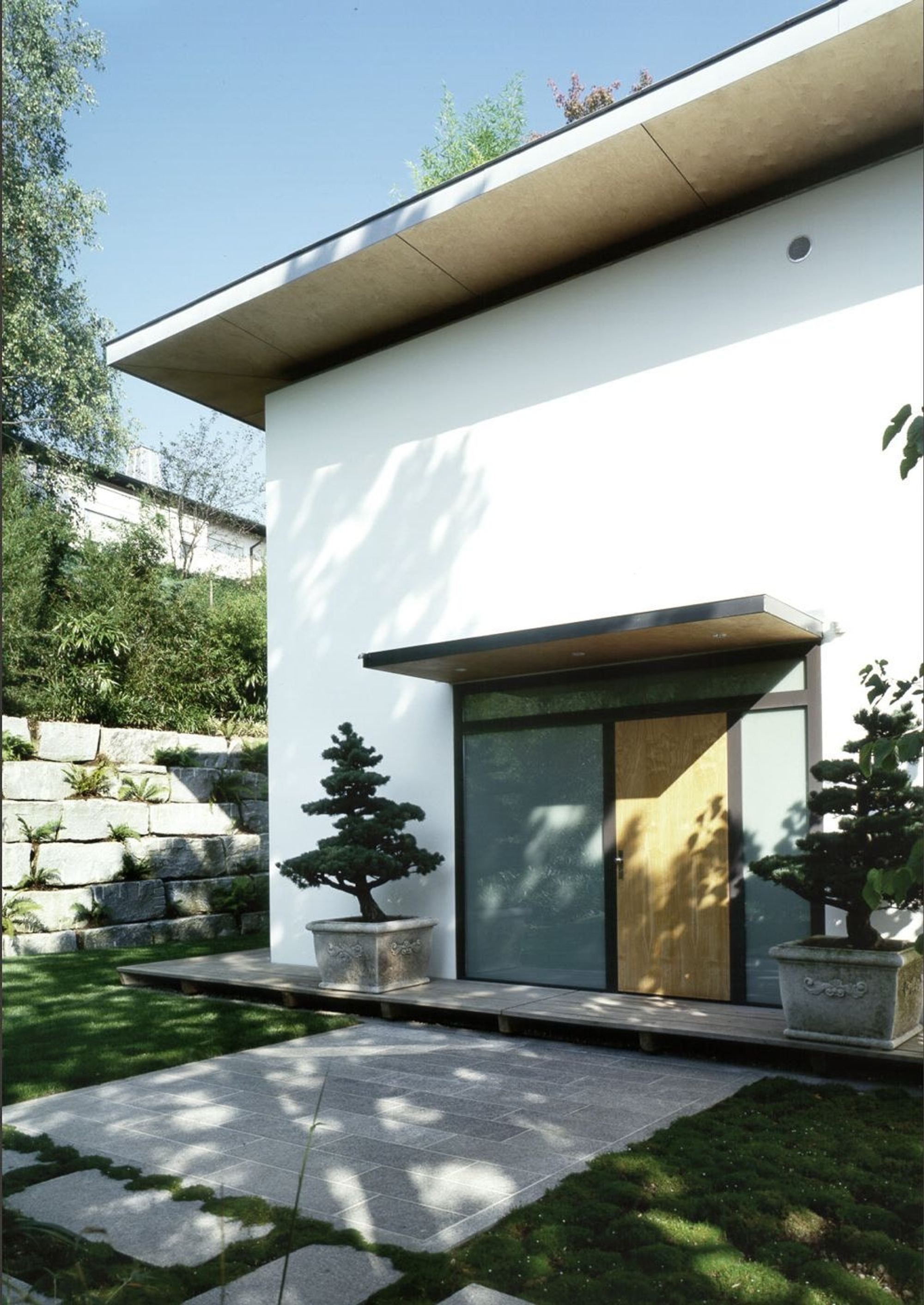 Entrance with bonsai and natural stone wall – Single-family house