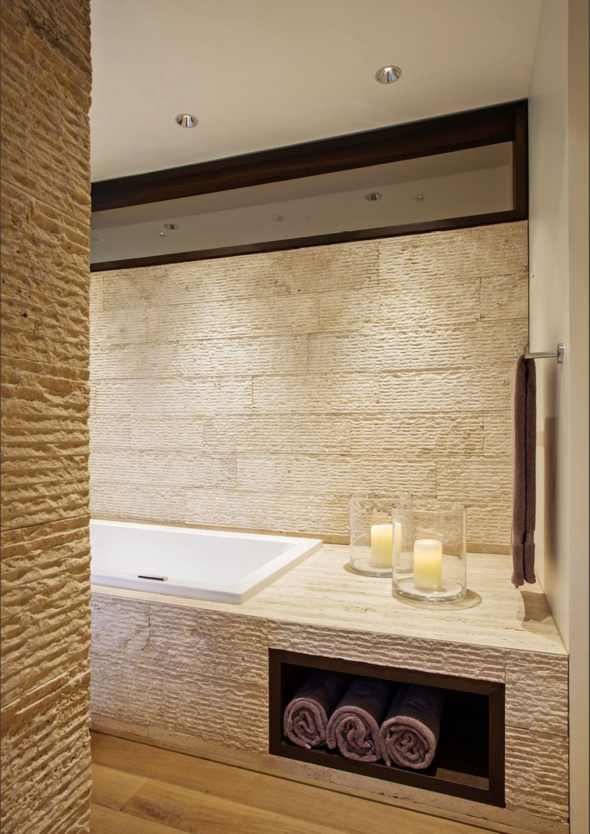 Bathtub with natural stone wall and candles – Apartment building in Uitikon