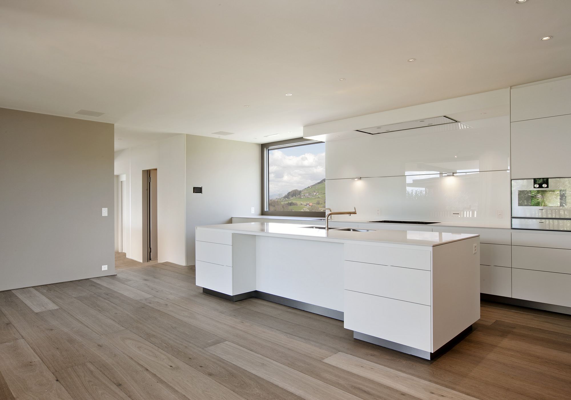 Open kitchen with white island and oak floor – Single-family house in Schindellegi