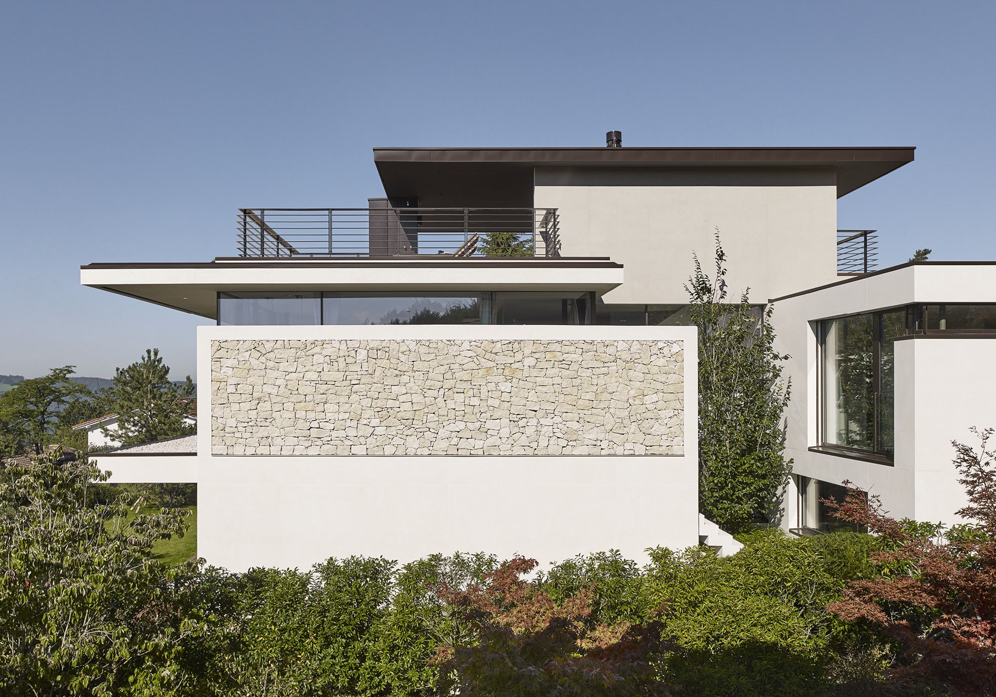 Side view with natural stone wall and roof terrace – Single-family house in Uitikon